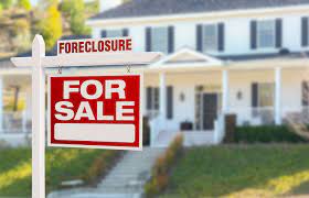 foreclosure for sale sign in front of white home.